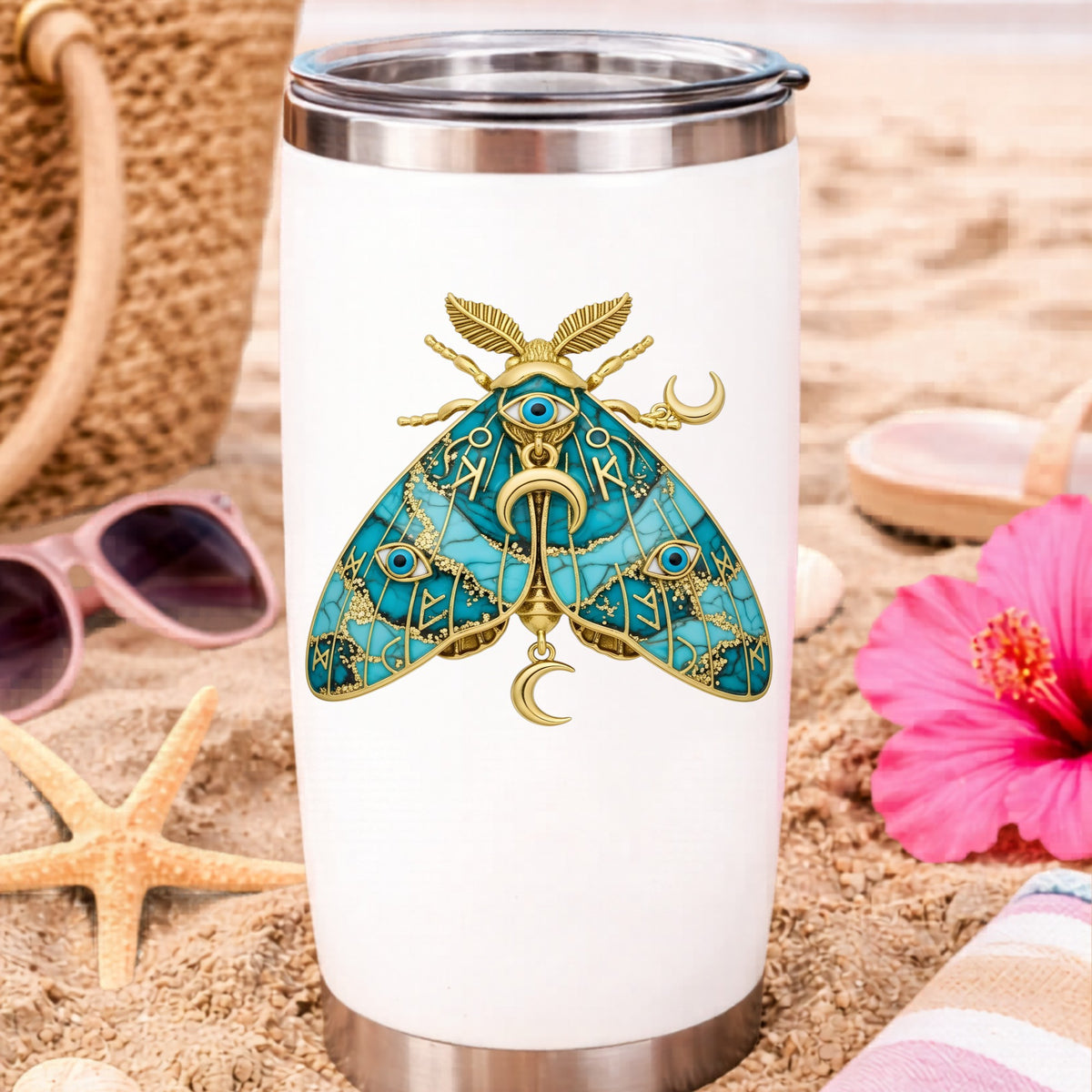 Teal Evil Eye Moth UV DTF sticker applied to a white travel tumbler on beach sand