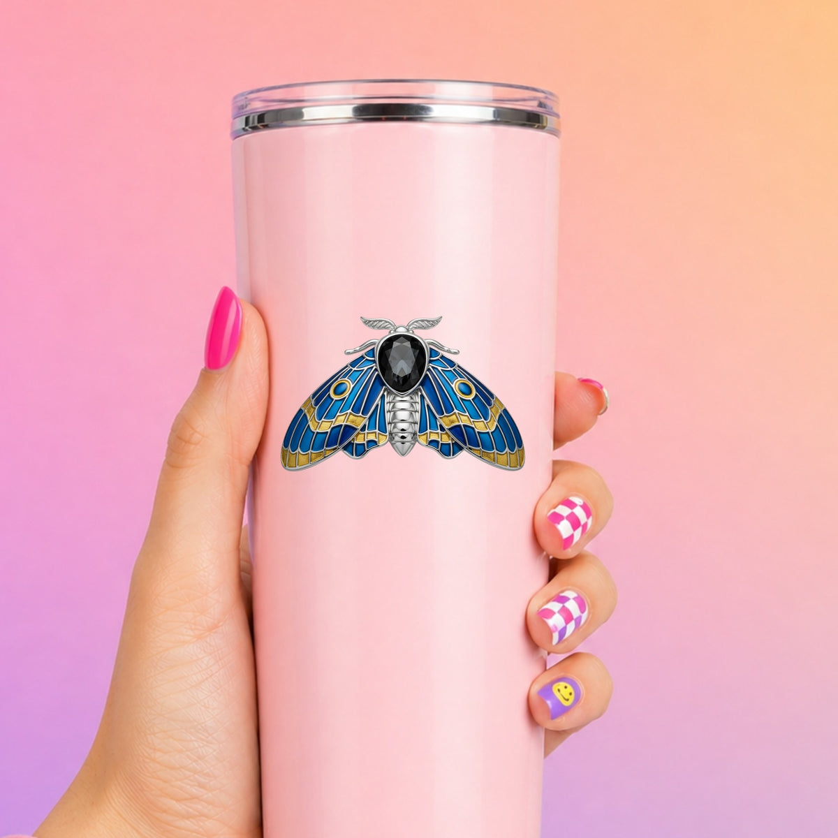 Silver Blue Enamel Moth UV DTF sticker applied to a tall pink tumbler on a pink and orange background