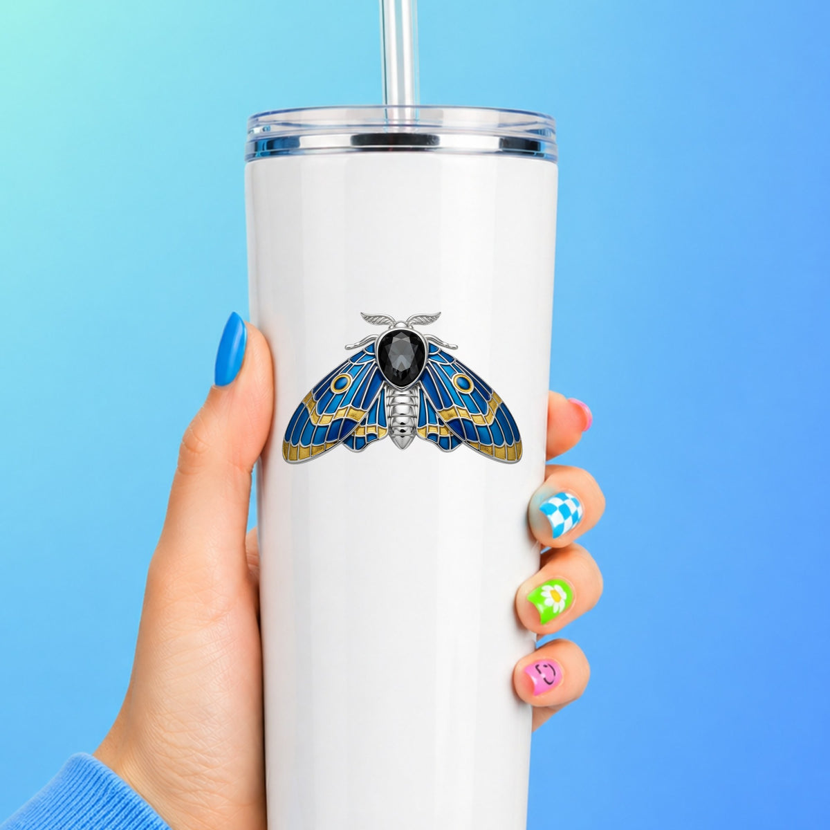 Silver Blue Enamel Moth UV DTF sticker applied to a white straw tumbler on a blue background