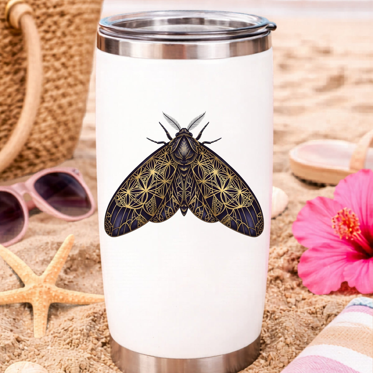 Sacred Geometry Moth UV DTF sticker applied to a white travel tumbler on beach sand