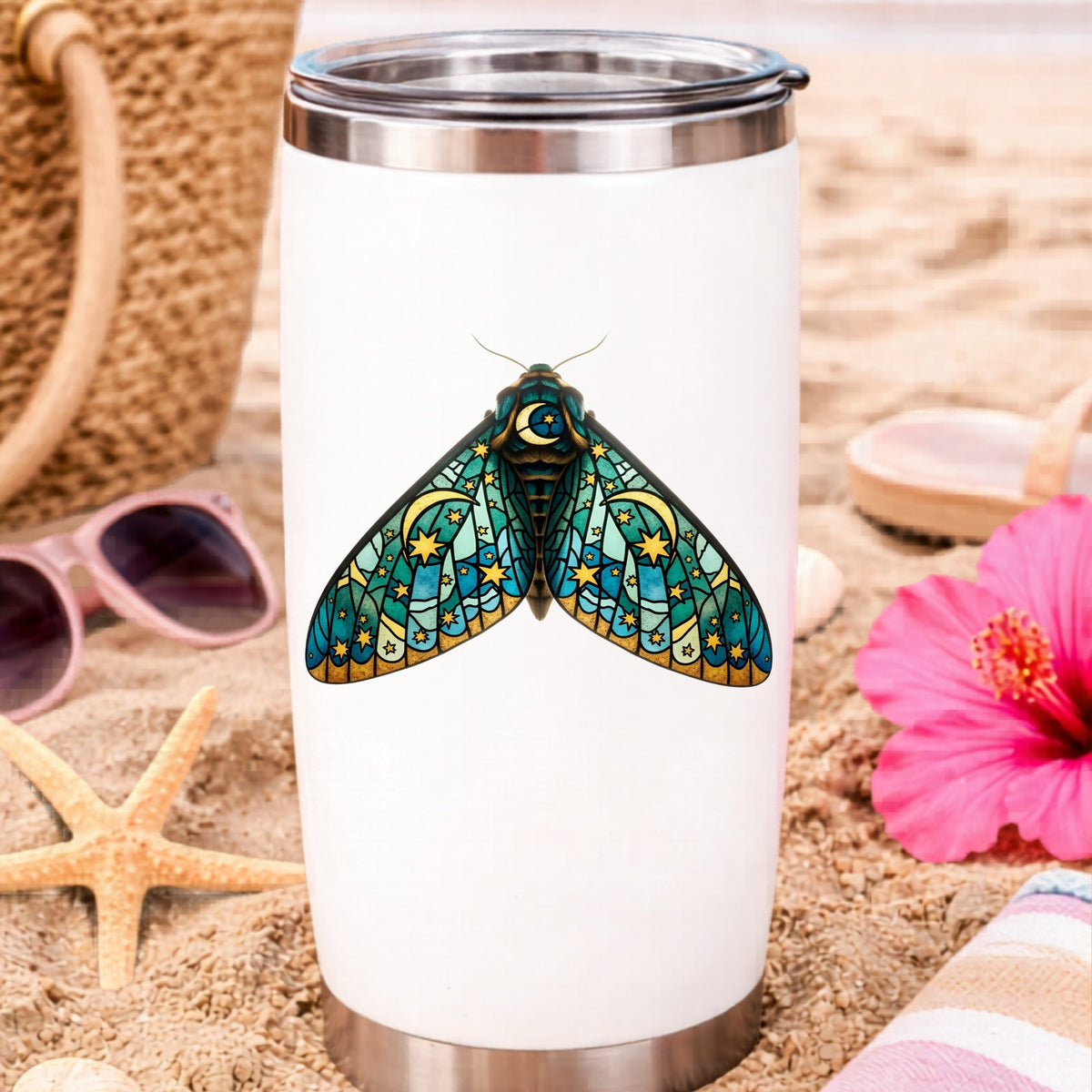 Stained Glass Moon Moth UV DTF sticker applied to a white travel tumbler on beach sand