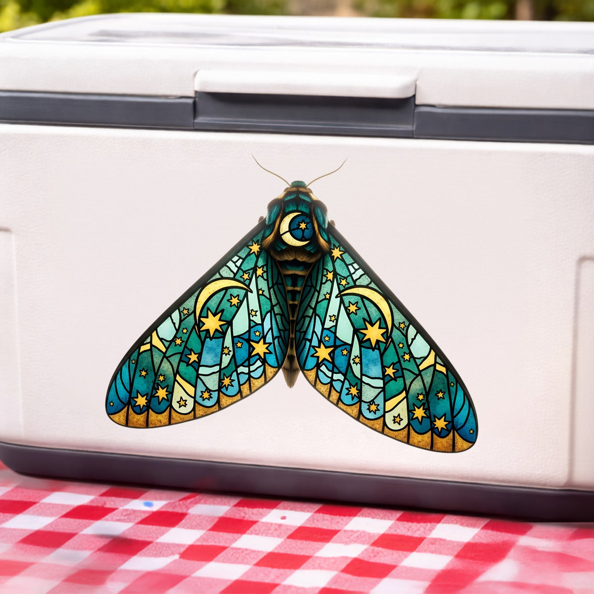 Stained Glass Moon Moth UV DTF sticker applied to a white cooler on a red gingham cloth