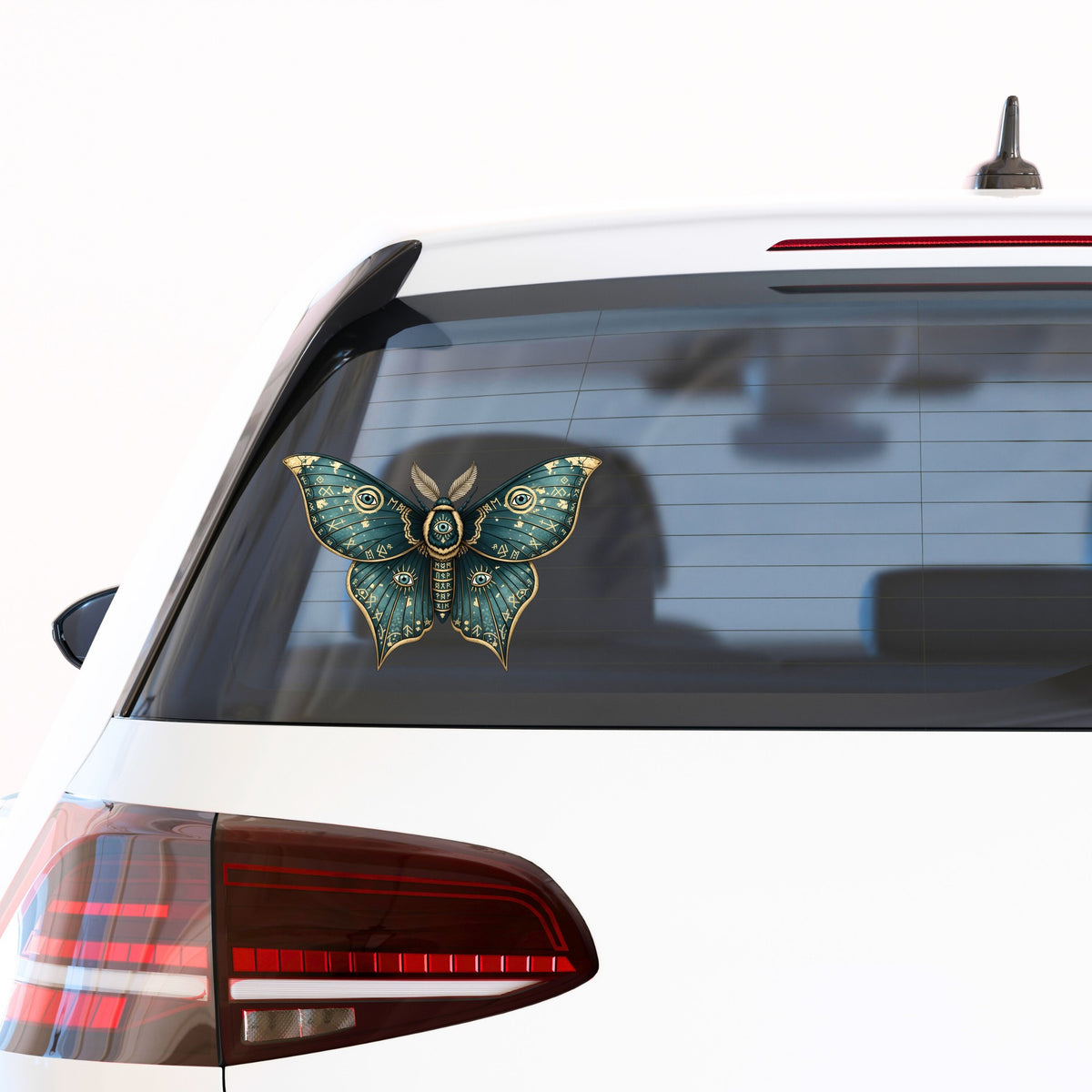 Teal Rune Moth All Seeing Eye UV DTF sticker applied to the rear window of a white car