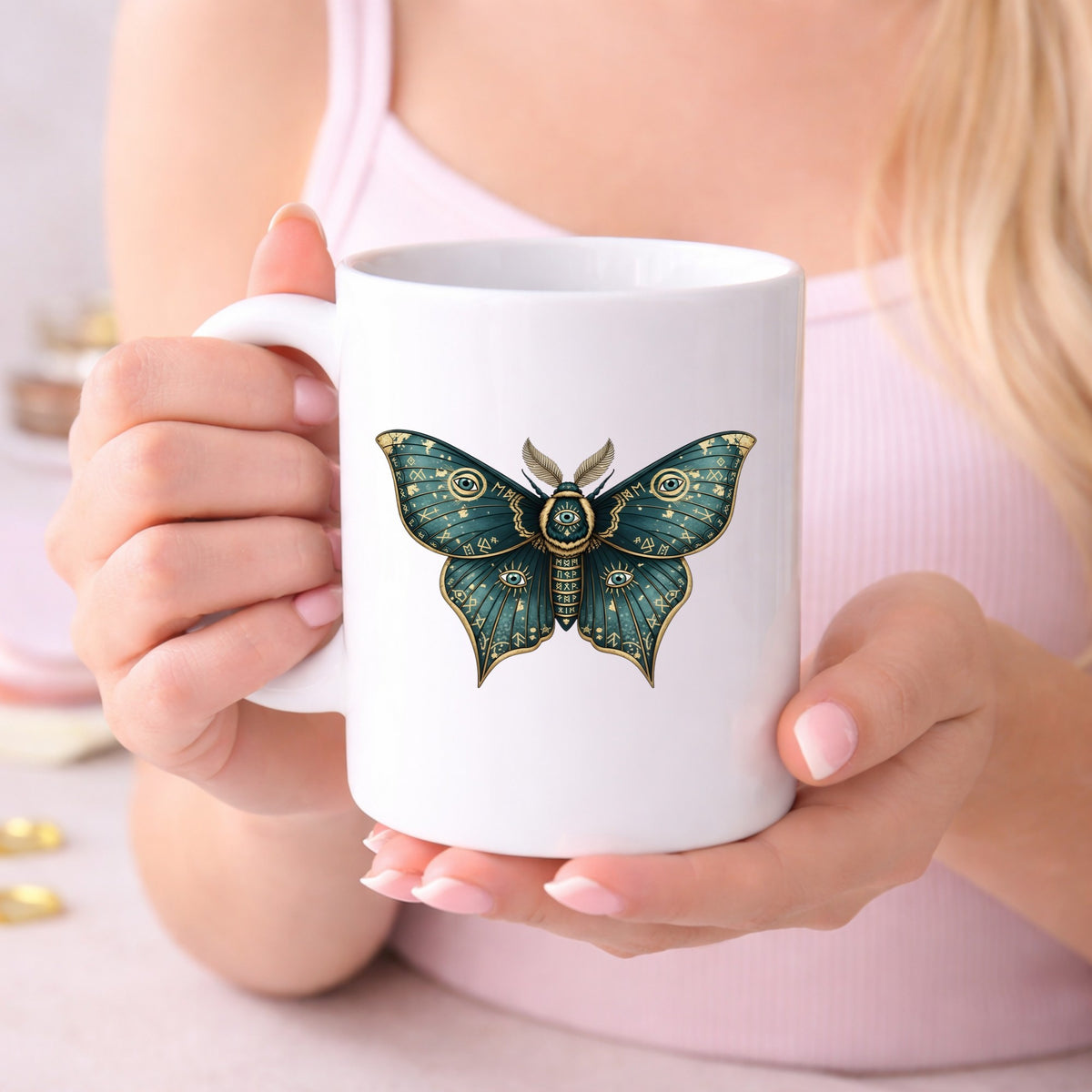 Teal Rune Moth All Seeing Eye UV DTF sticker applied to a white coffee mug held in both hands