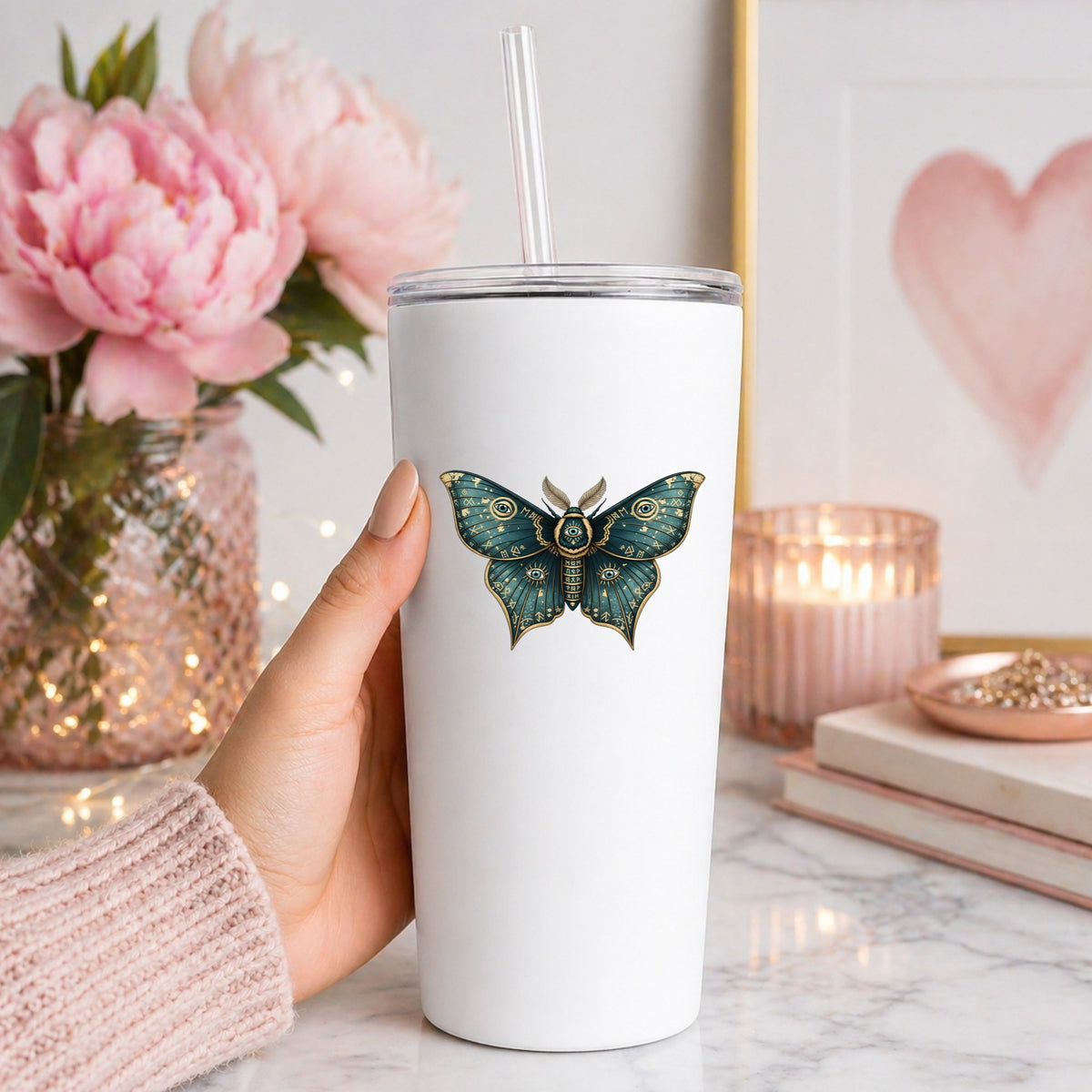 Teal Rune Moth All Seeing Eye UV DTF sticker applied to a white straw tumbler beside pink peonies