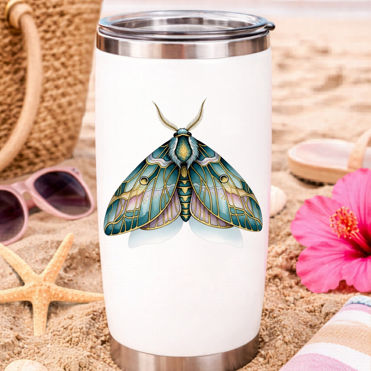 Pastel Teal Pink Moth UV DTF sticker applied to a white travel tumbler on beach sand