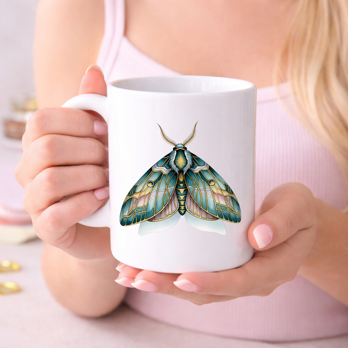 Pastel Teal Pink Moth UV DTF sticker applied to a white coffee mug held in both hands