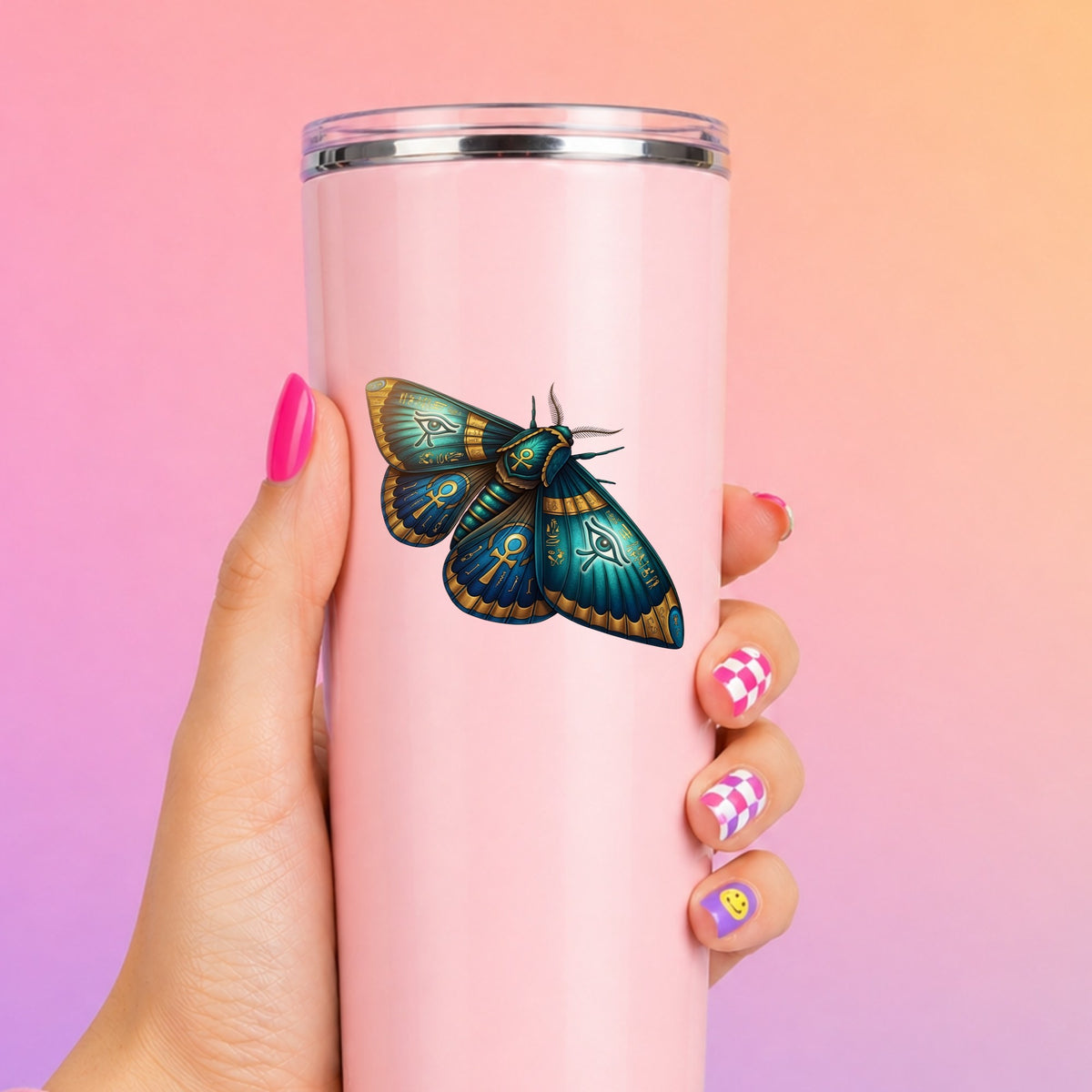 Egyptian Eye Of Horus Moth UV DTF sticker applied to a tall pink tumbler on a pink and orange background