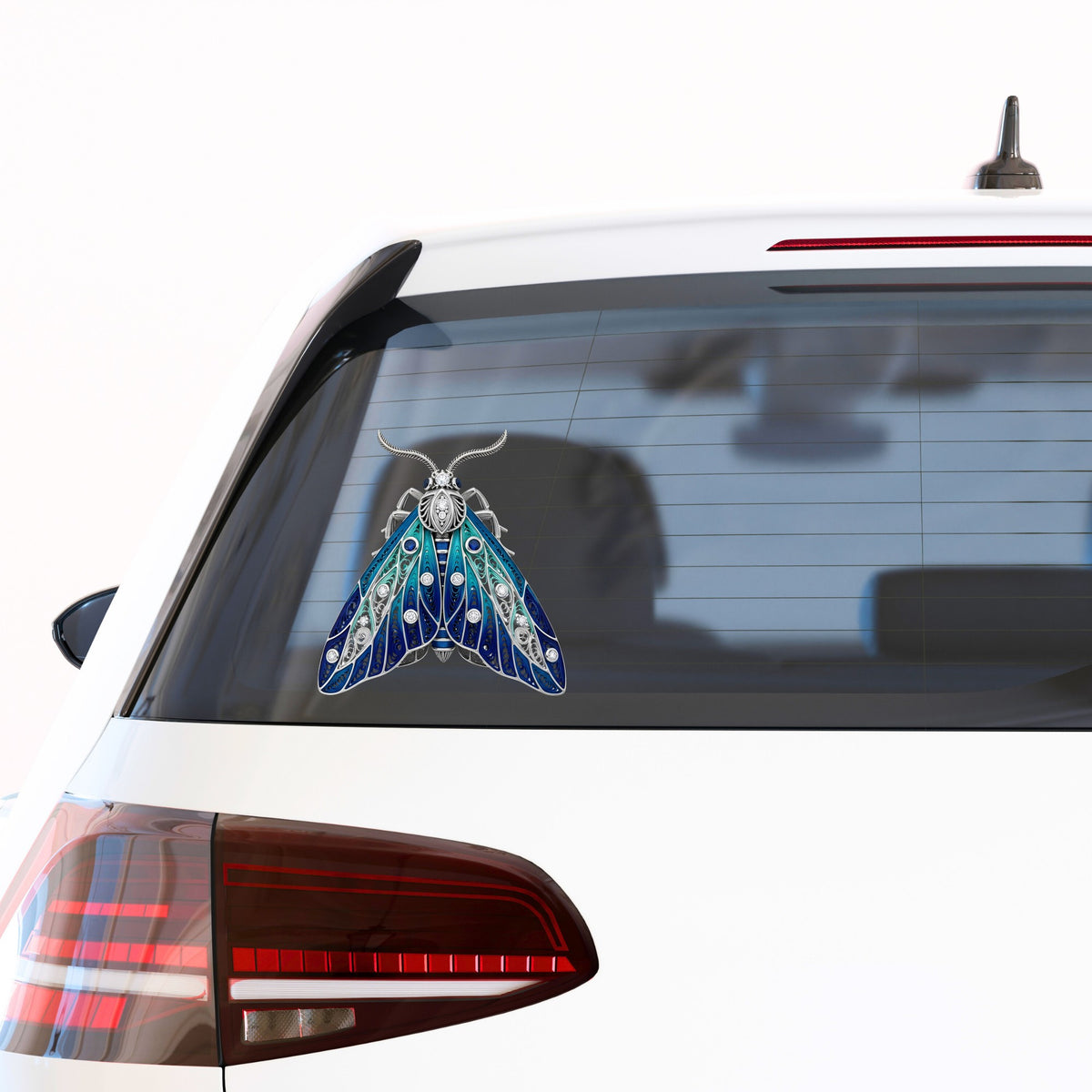 Silver Filigree Blue Moth UV DTF sticker applied to the rear window of a white car