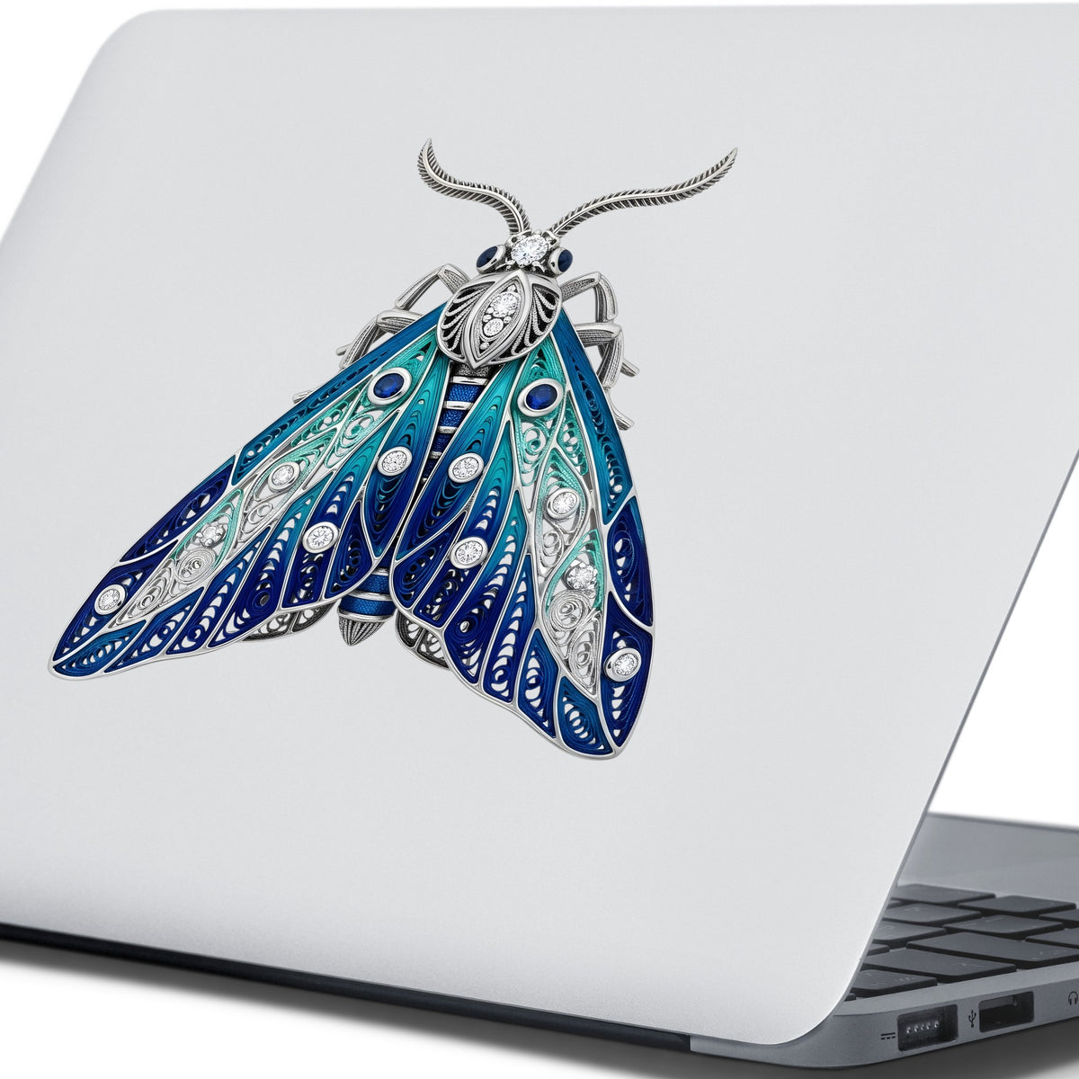 Silver Filigree Blue Moth UV DTF sticker applied to the lid of a silver laptop