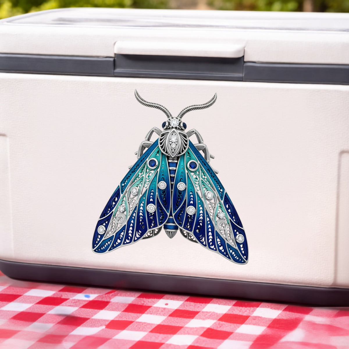 Silver Filigree Blue Moth UV DTF sticker applied to a white cooler on a red gingham cloth