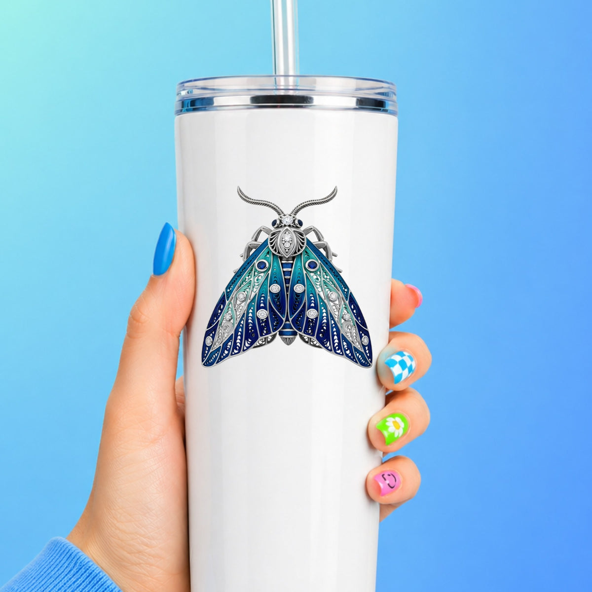 Silver Filigree Blue Moth UV DTF sticker applied to a white straw tumbler on a blue background