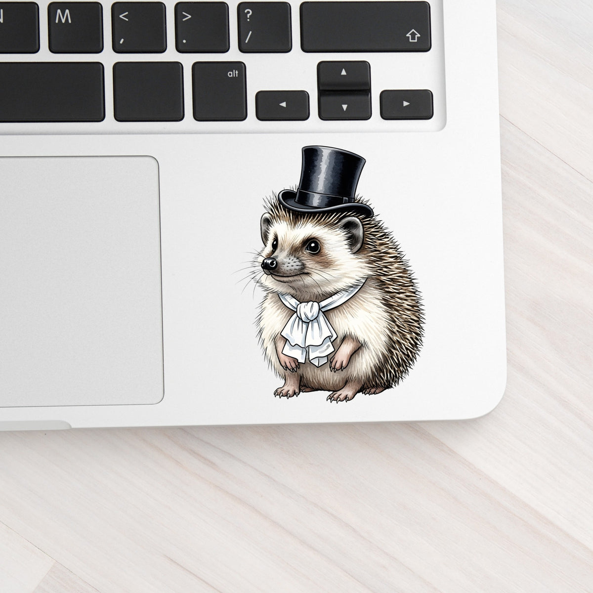 Hedgehog In Top Hat UV DTF sticker applied to a silver laptop beside the keyboard