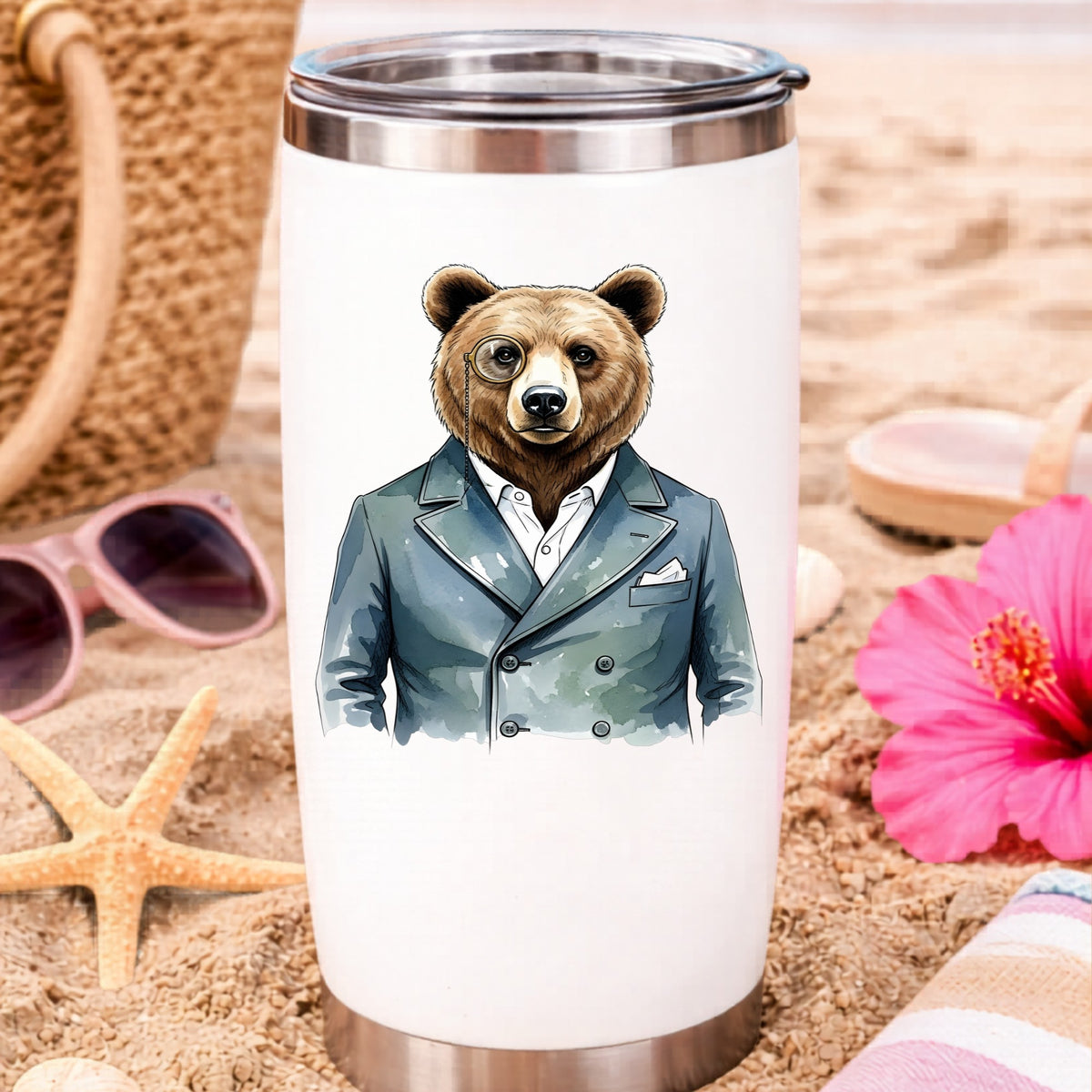 Bear With Monocle Blue Suit UV DTF sticker applied to a white travel tumbler on beach sand