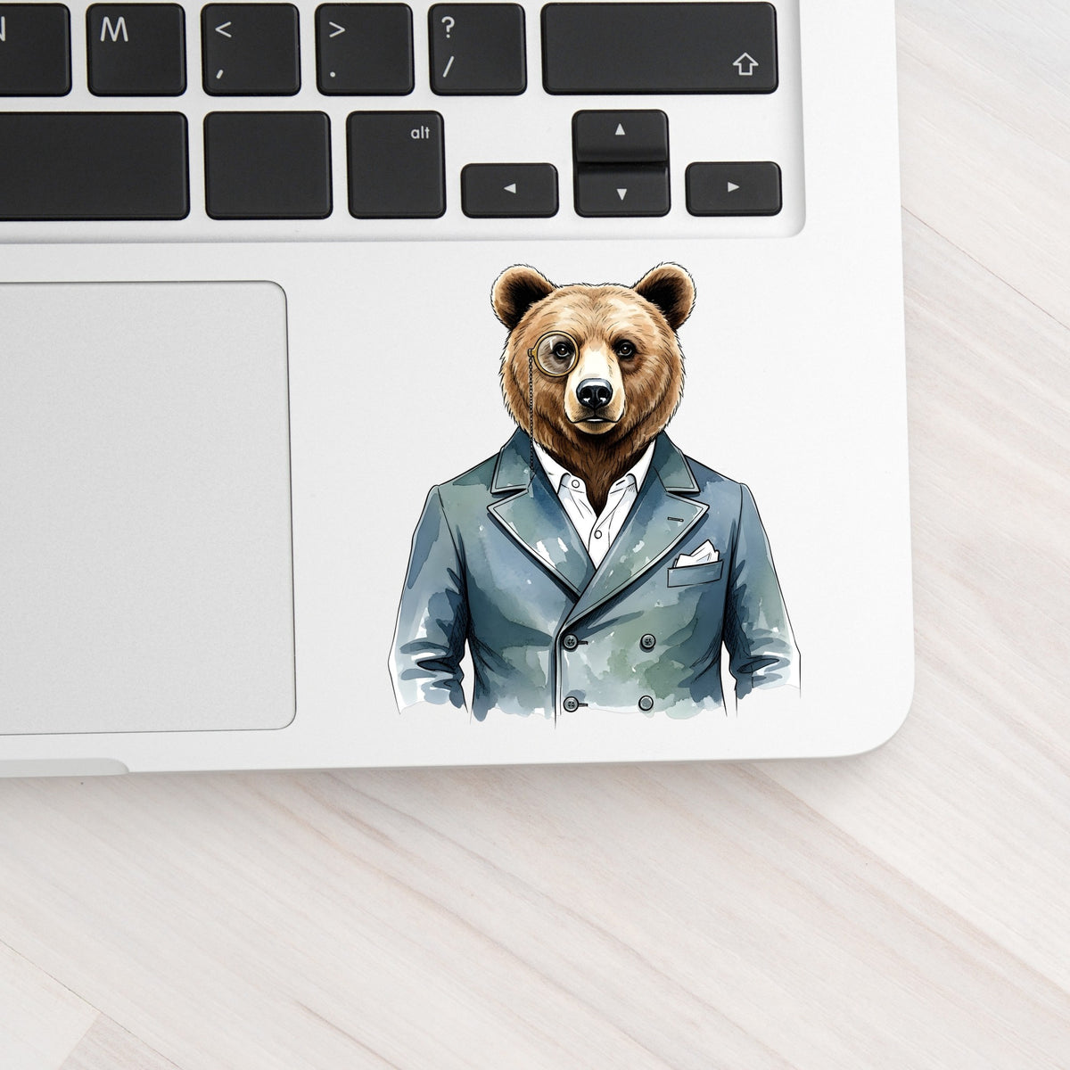 Bear With Monocle Blue Suit UV DTF sticker applied to a silver laptop beside the keyboard