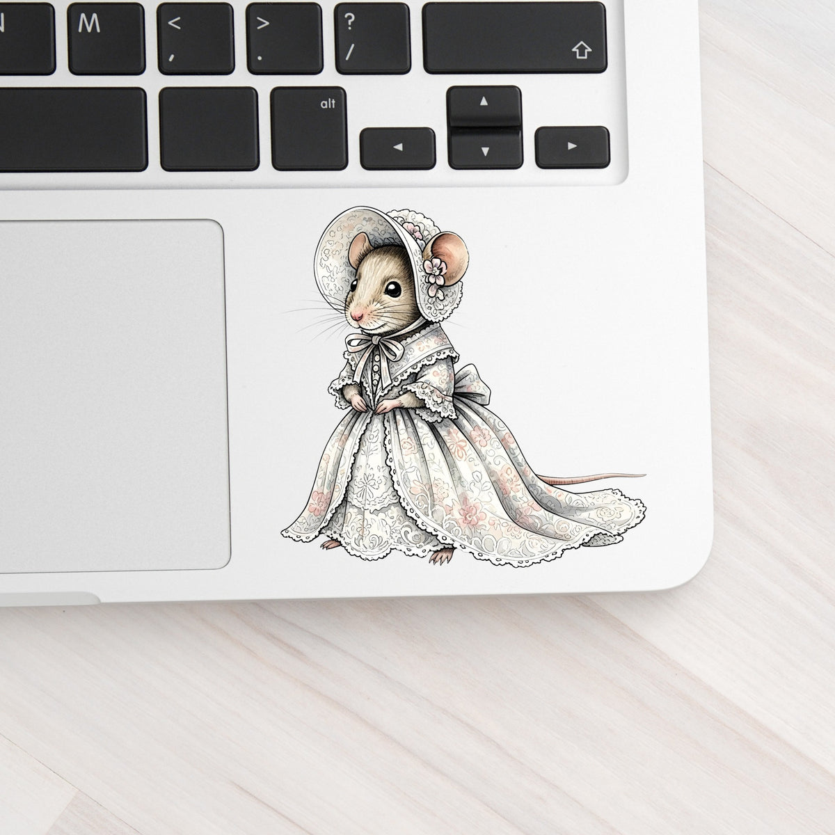 Mouse In Lace Bonnet Dress UV DTF sticker applied to a silver laptop beside the keyboard