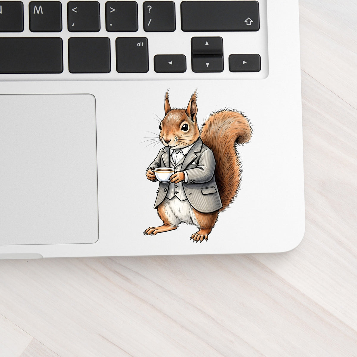 Red Squirrel Holding Teacup UV DTF sticker applied to a silver laptop beside the keyboard