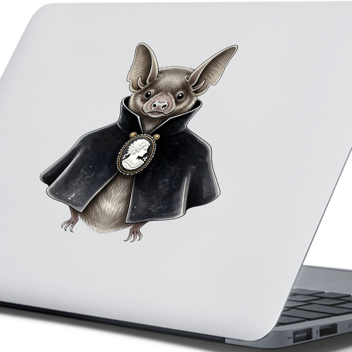 Bat In Black Cape Cameo UV DTF sticker applied to the lid of a silver laptop