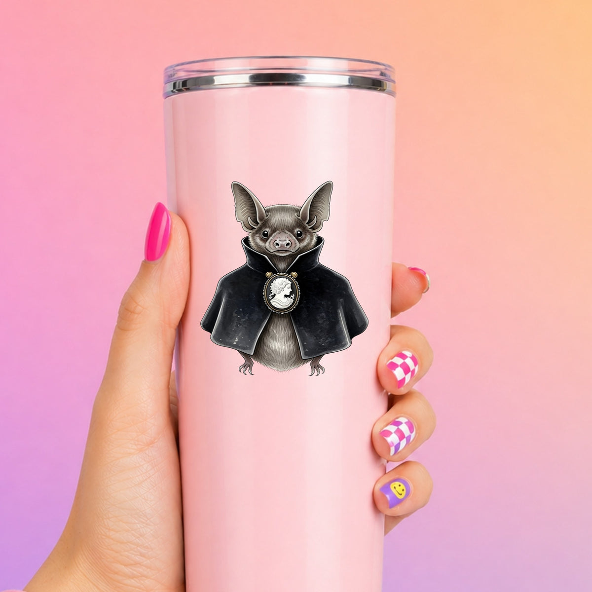 Bat In Black Cape Cameo UV DTF sticker applied to a tall pink tumbler on a pink and orange background