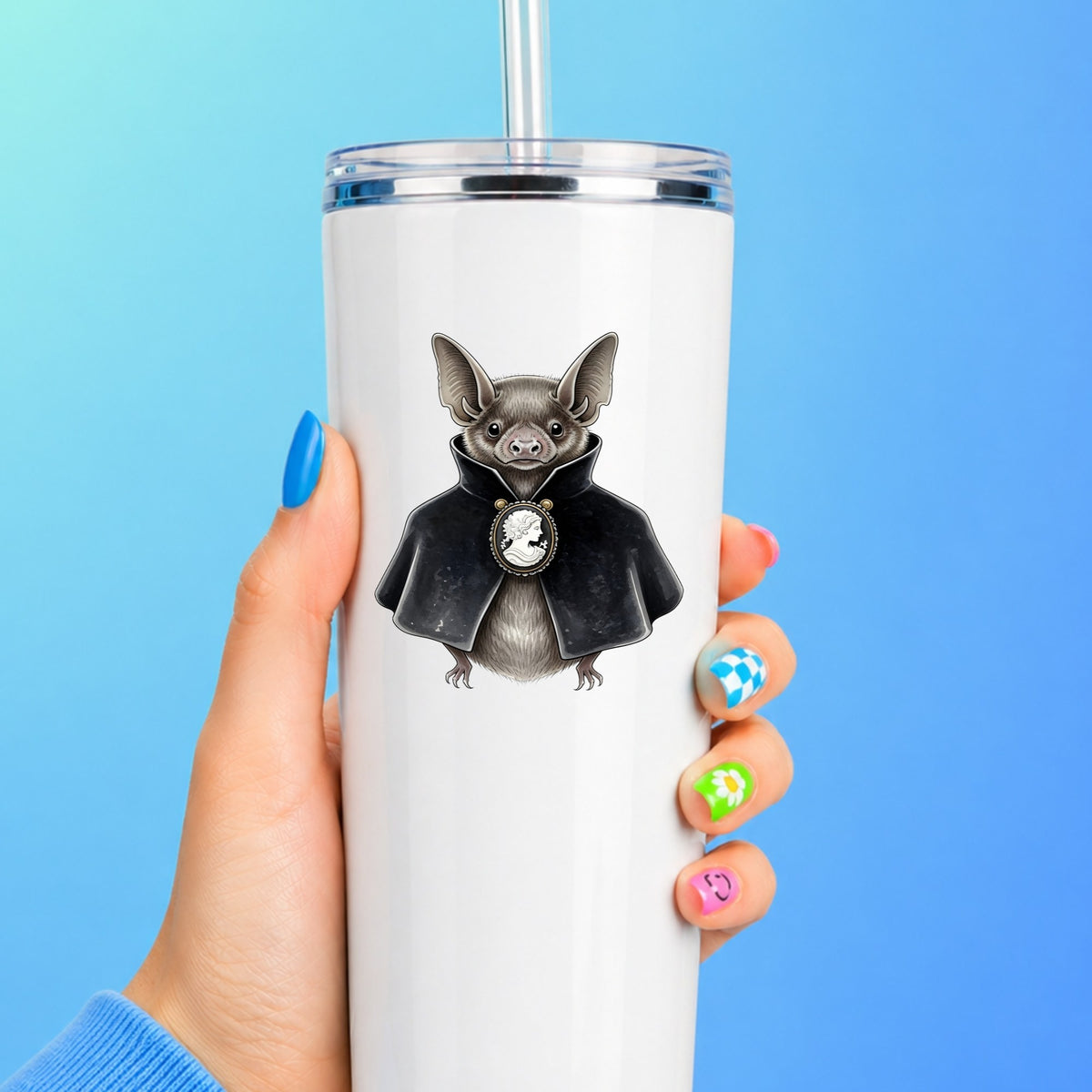 Bat In Black Cape Cameo UV DTF sticker applied to a white straw tumbler on a blue background