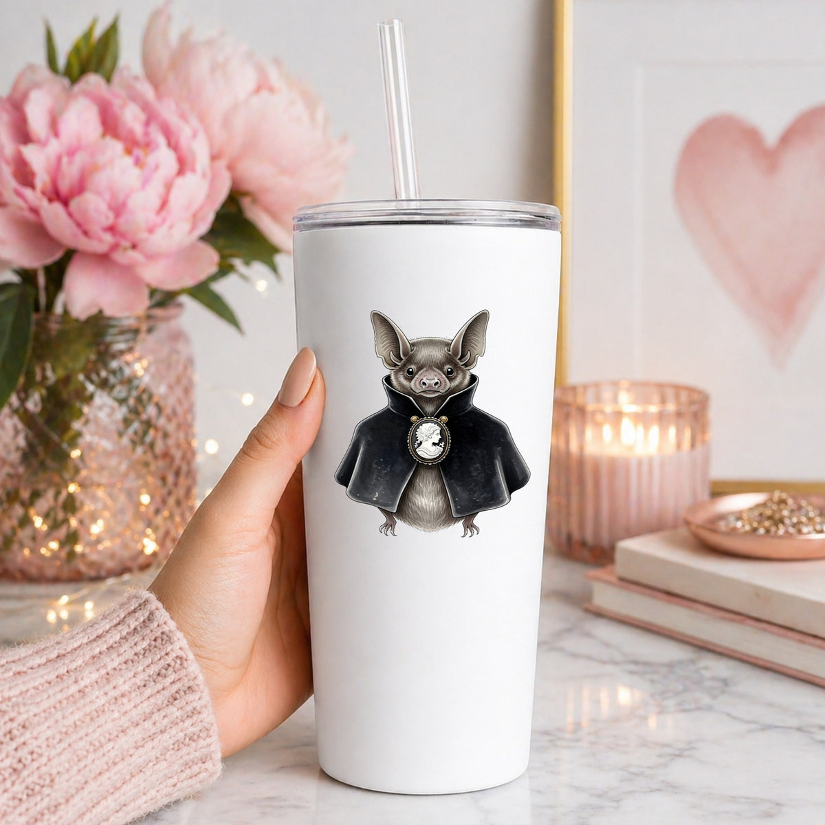 Bat In Black Cape Cameo UV DTF sticker applied to a white straw tumbler beside pink peonies