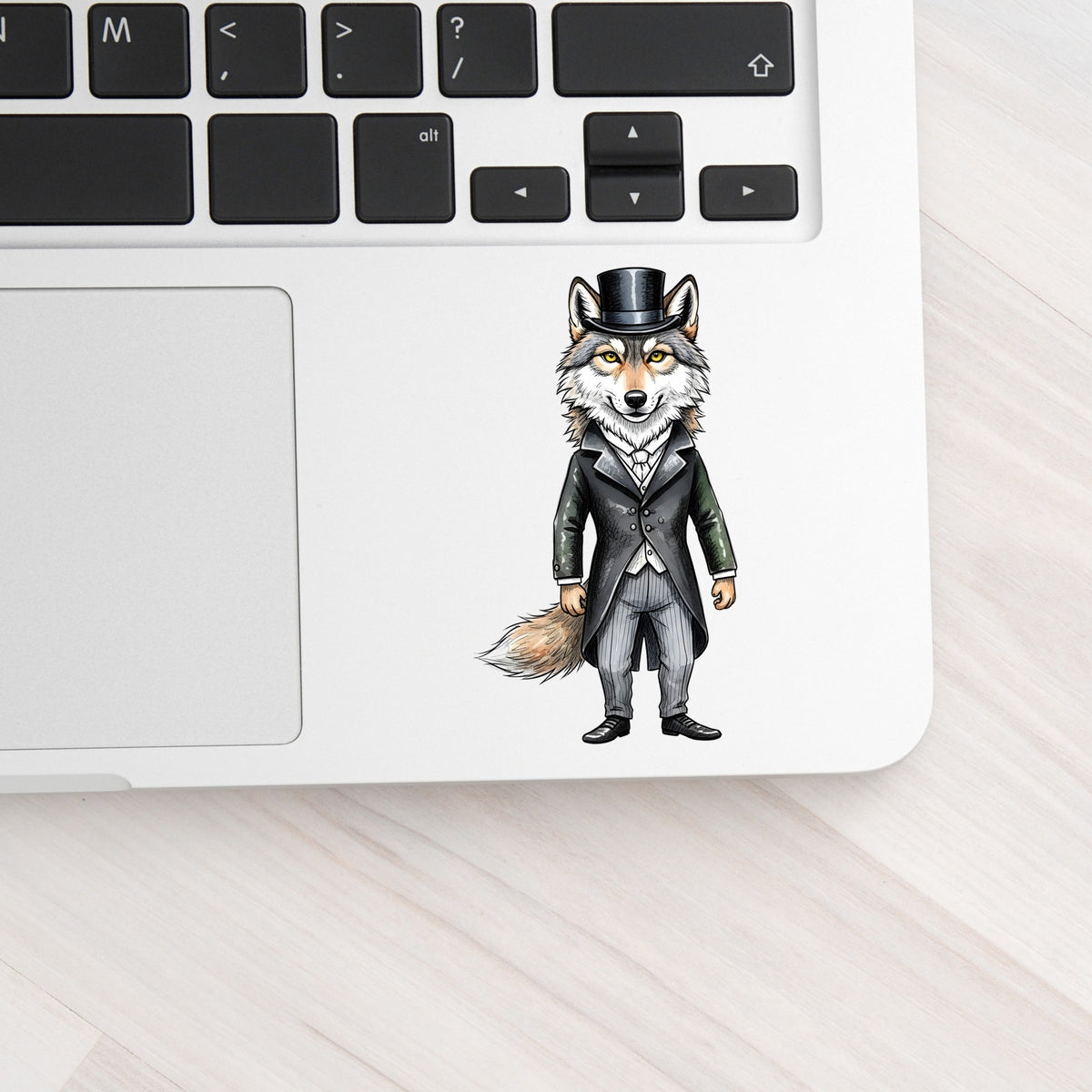 Gray Wolf Top Hat Tailcoat UV DTF sticker applied to a silver laptop beside the keyboard