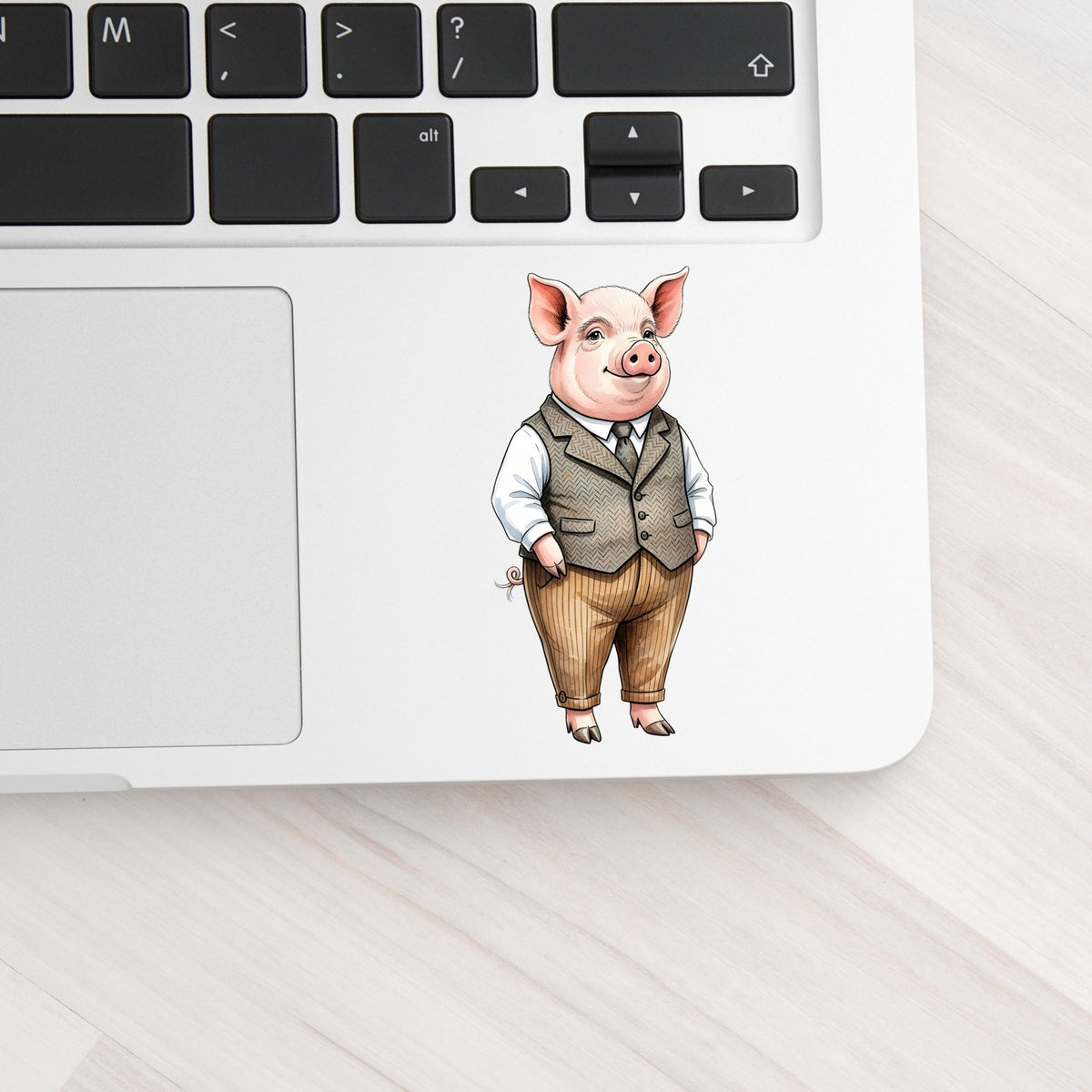 Pig In Tweed Vest UV DTF sticker applied to a silver laptop beside the keyboard