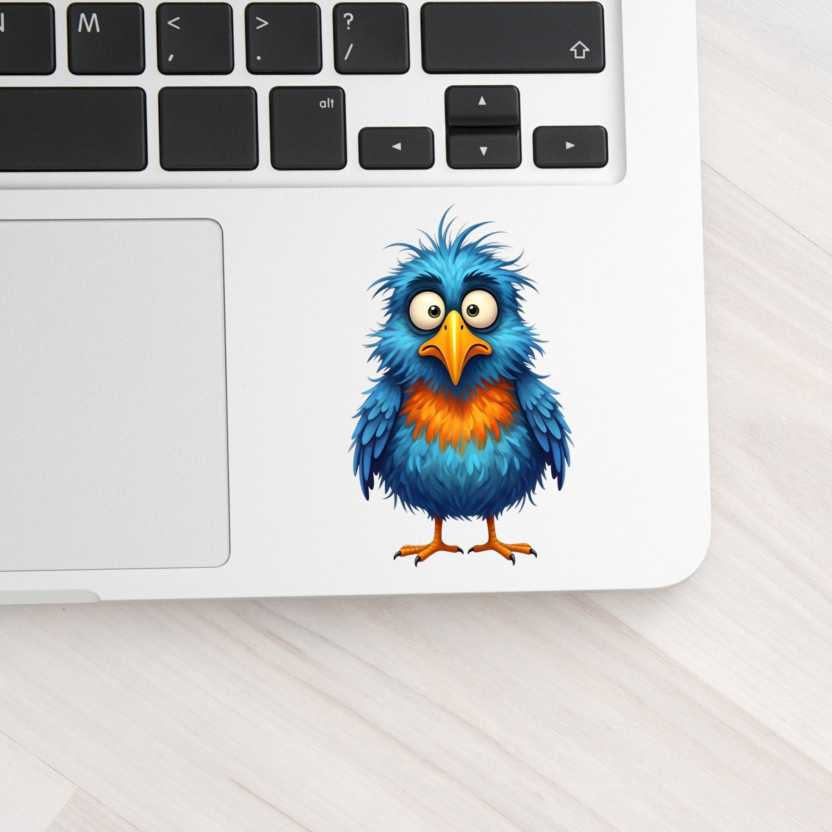 Wide Eyed Shaggy Blue Bird UV DTF sticker applied to a silver laptop beside the keyboard