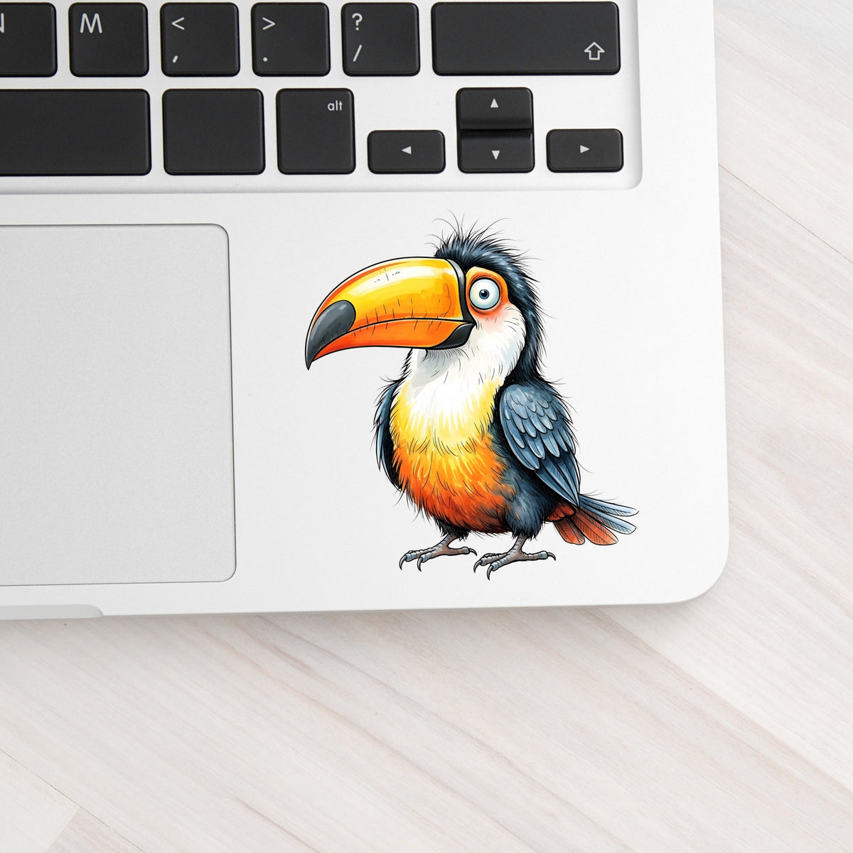 Toucan Big Orange Beak UV DTF sticker applied to a silver laptop beside the keyboard