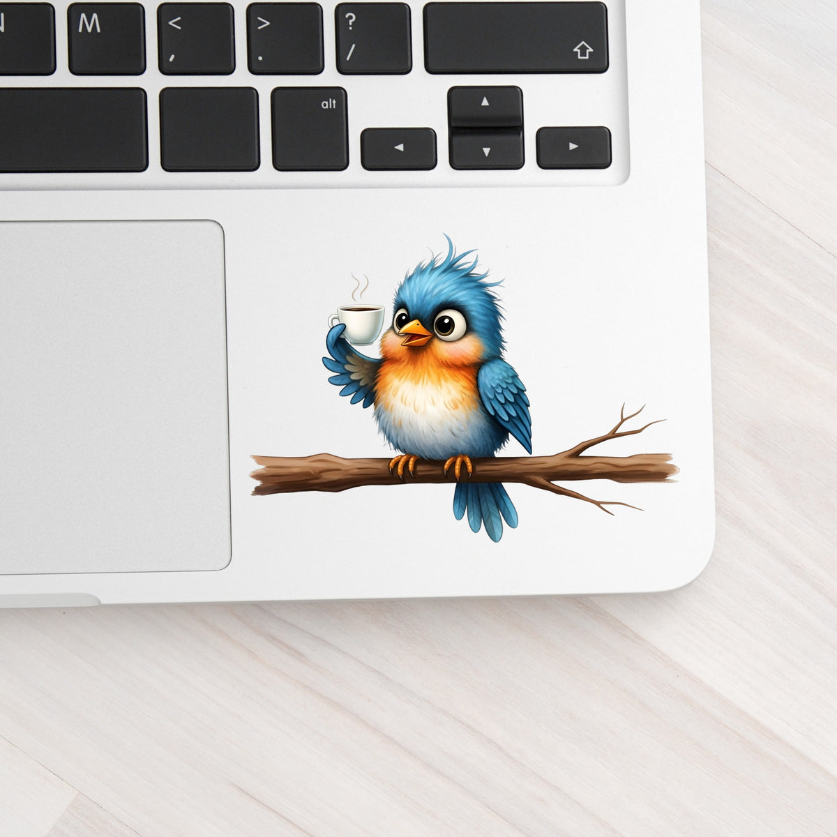 Bird Drinking Coffee On Branch UV DTF sticker applied to a silver laptop beside the keyboard