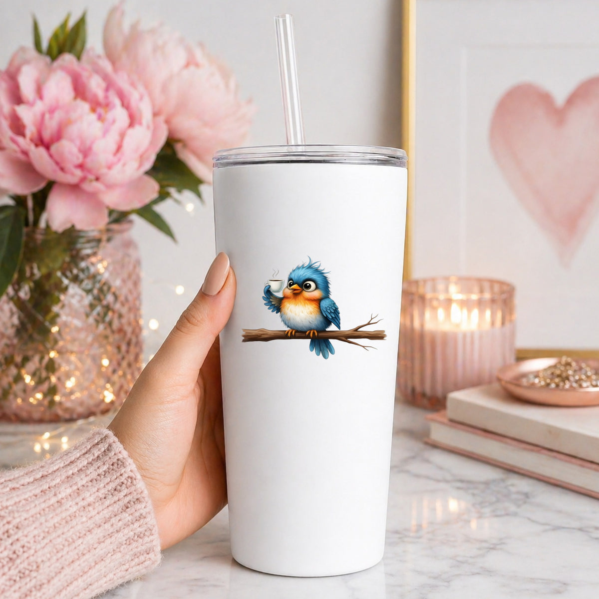 Bird Drinking Coffee On Branch UV DTF sticker applied to a white straw tumbler beside pink peonies