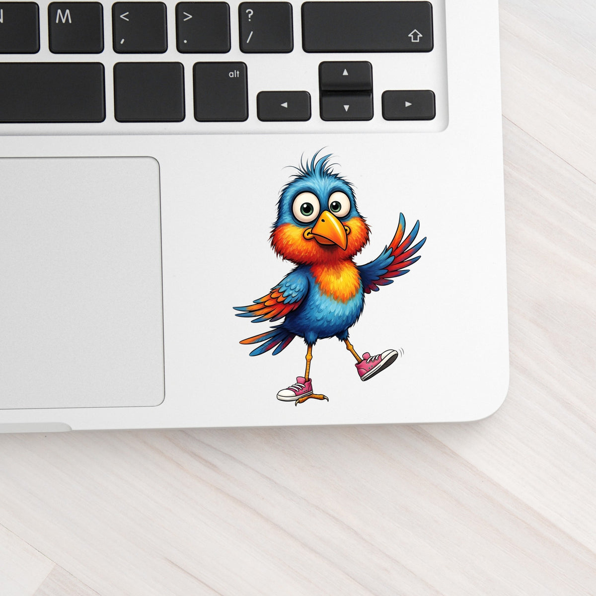 Bird In Pink Sneakers UV DTF sticker applied to a silver laptop beside the keyboard