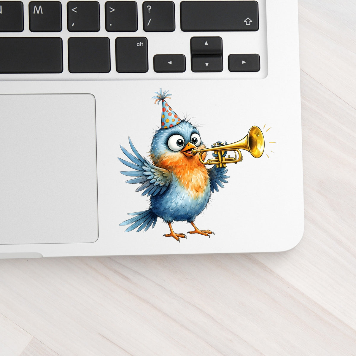 Party Hat Bird Trumpet UV DTF sticker applied to a silver laptop beside the keyboard