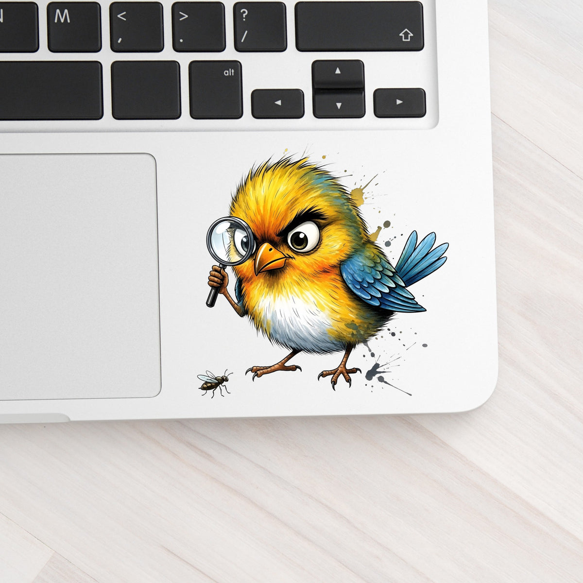 Yellow Bird Magnifying Glass Bug UV DTF sticker applied to a silver laptop beside the keyboard