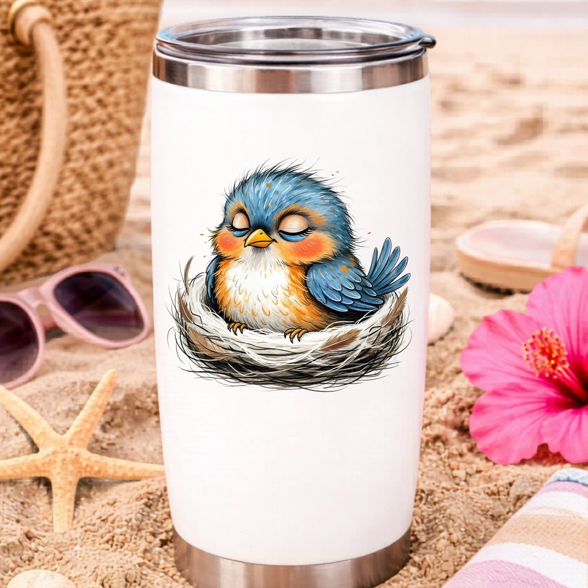 Sleeping Bird In Nest UV DTF sticker applied to a white travel tumbler on beach sand