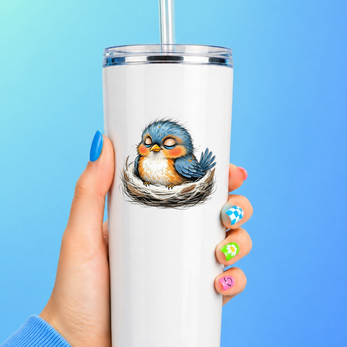 Sleeping Bird In Nest UV DTF sticker applied to a white straw tumbler on a blue background