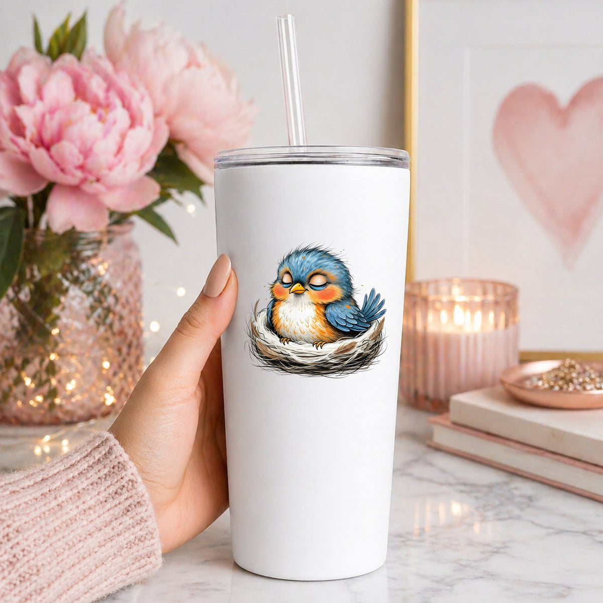 Sleeping Bird In Nest UV DTF sticker applied to a white straw tumbler beside pink peonies