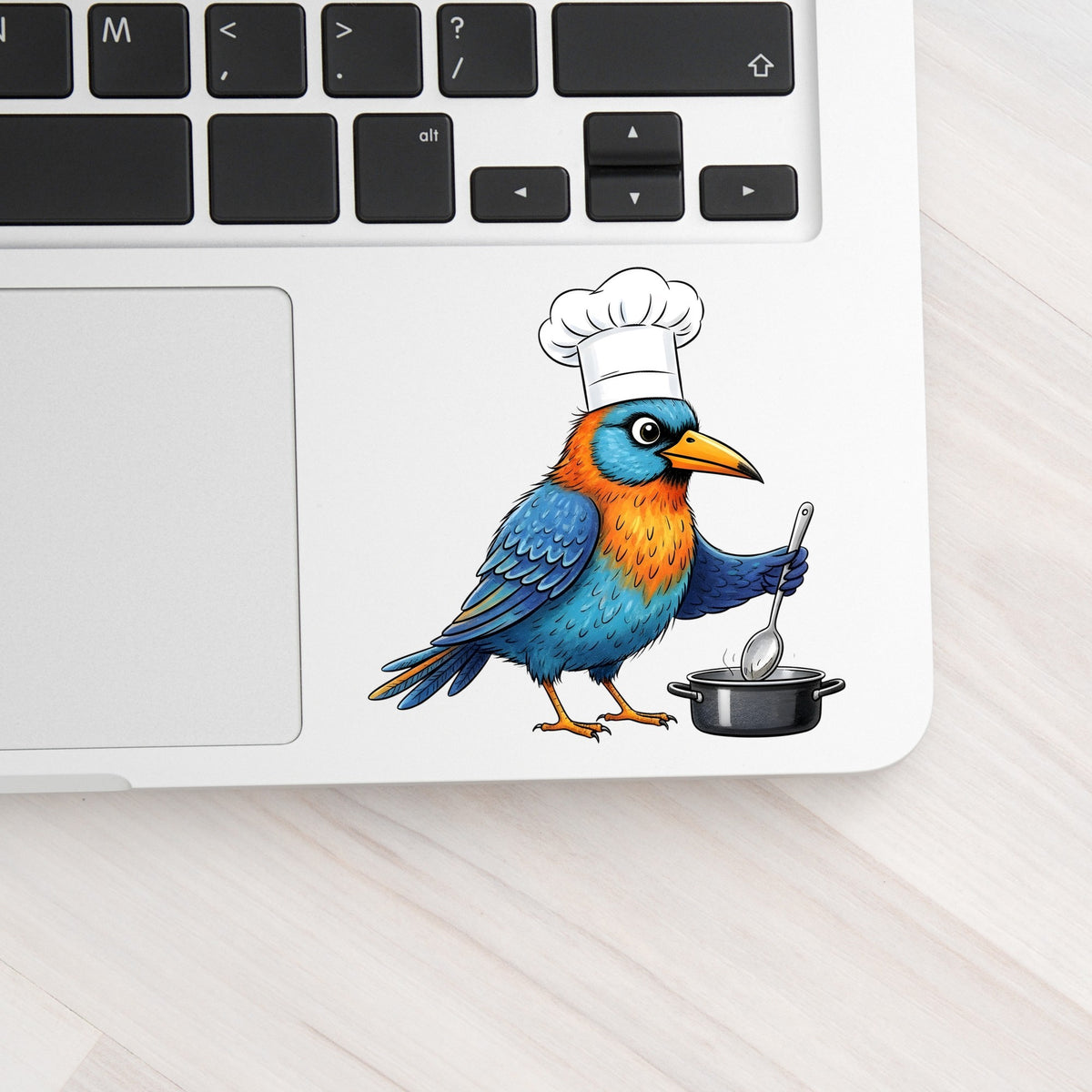 Chef Bird Cooking Pot UV DTF sticker applied to a silver laptop beside the keyboard