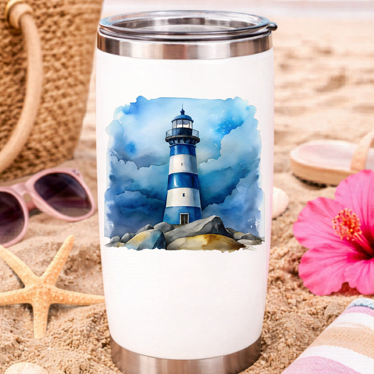 Blue Striped Lighthouse On Rocks UV DTF sticker applied to a white travel tumbler on beach sand