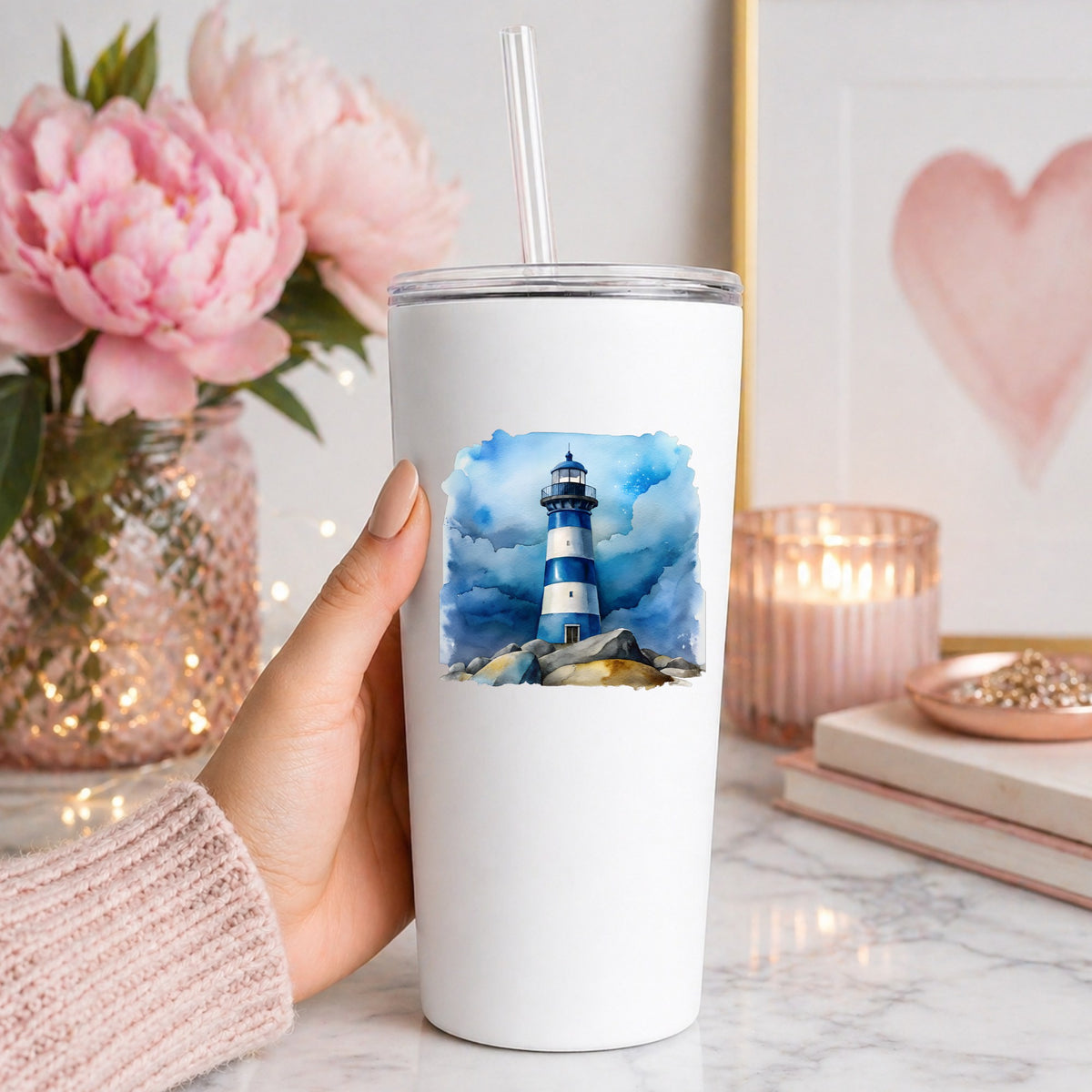 Blue Striped Lighthouse On Rocks UV DTF sticker applied to a white straw tumbler beside pink peonies