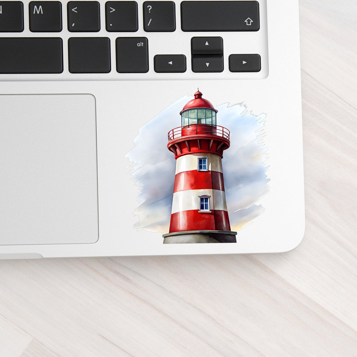 Red And White Lighthouse UV DTF sticker applied to a silver laptop beside the keyboard