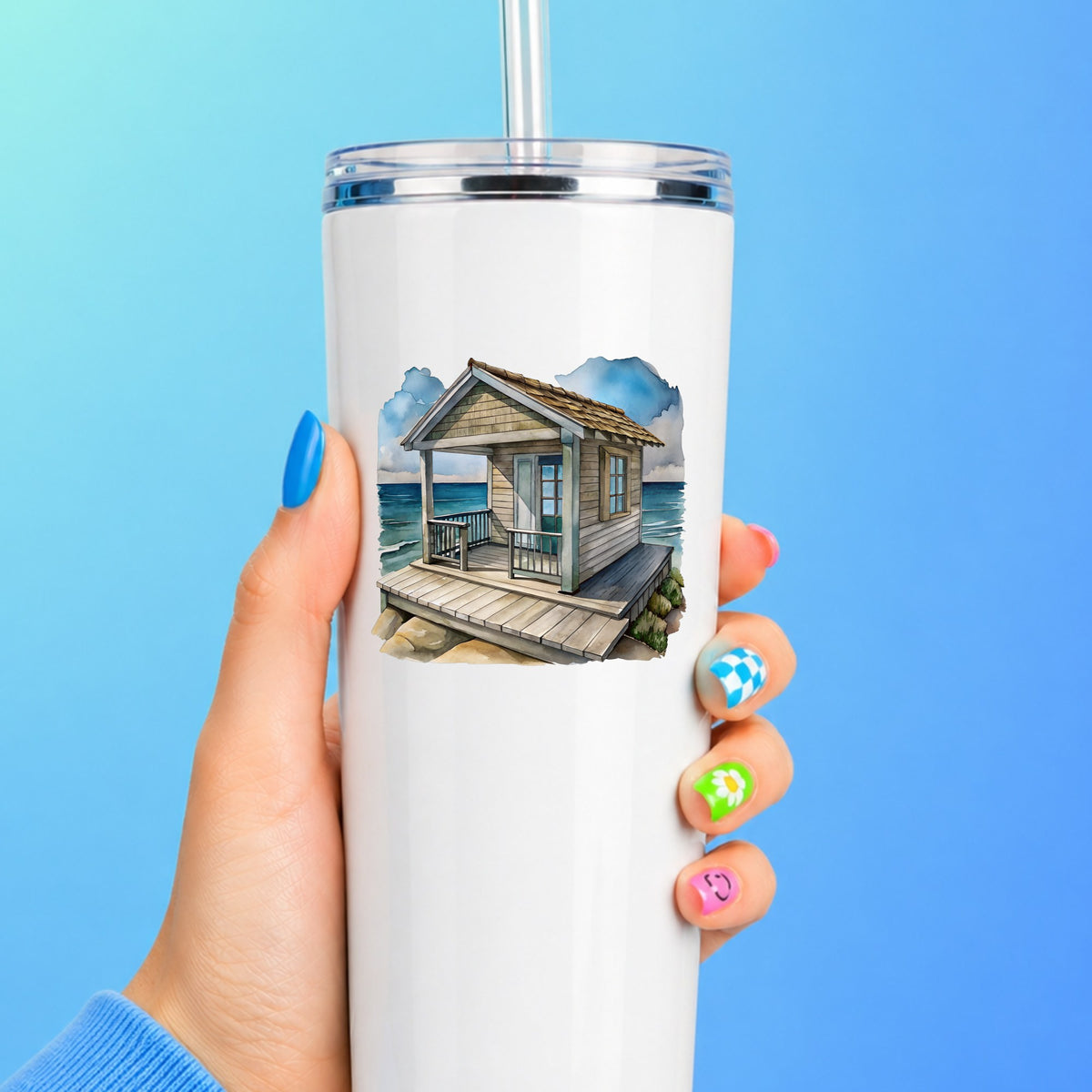 Beach Cottage Porch Ocean View UV DTF sticker applied to a white straw tumbler on a blue background