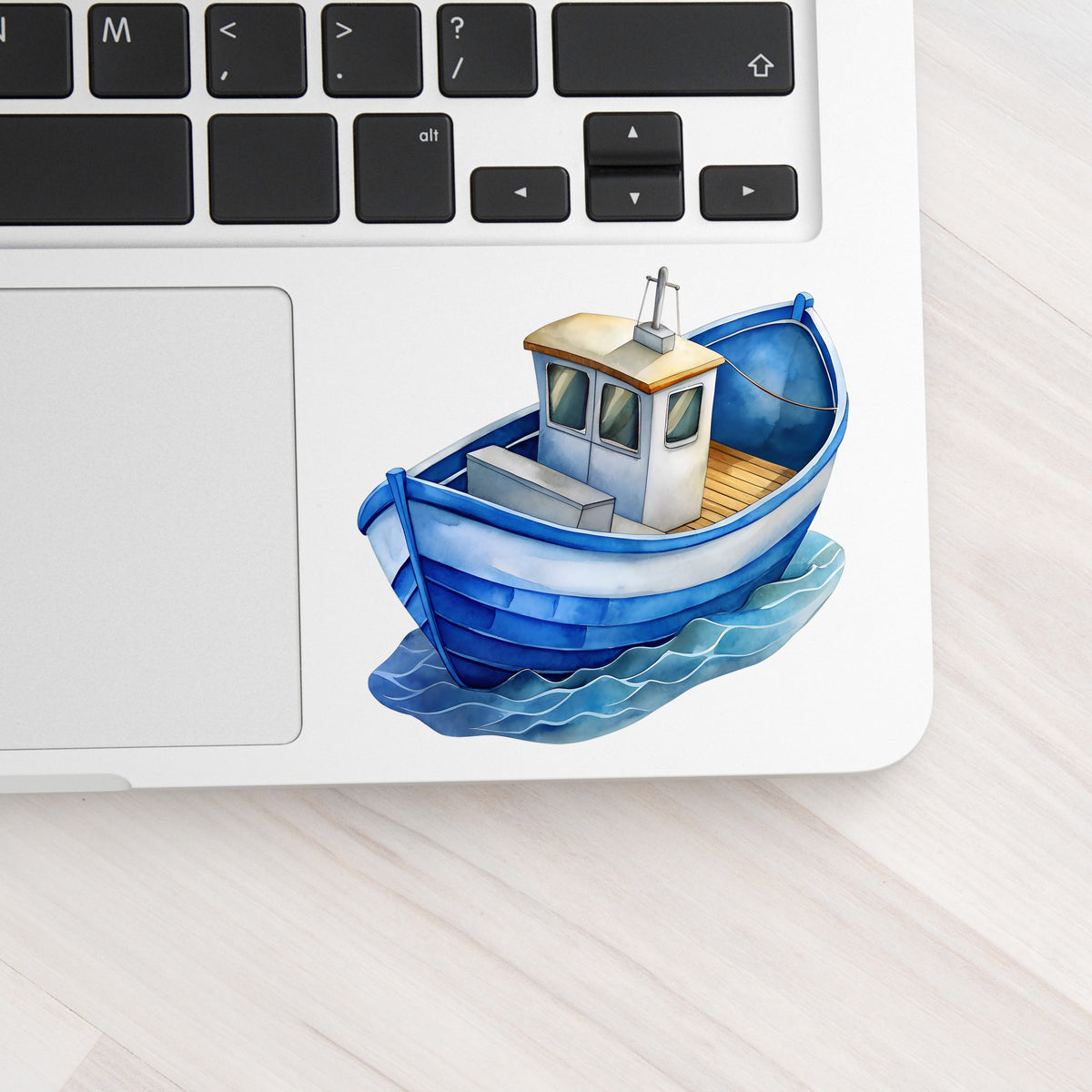 Blue Fishing Boat On Waves UV DTF sticker applied to a silver laptop beside the keyboard