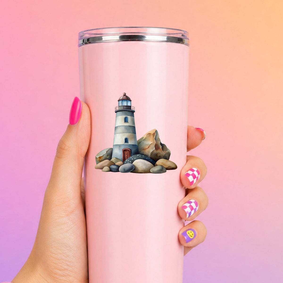 Lighthouse On Rocky Shore UV DTF sticker applied to a tall pink tumbler on a pink and orange background