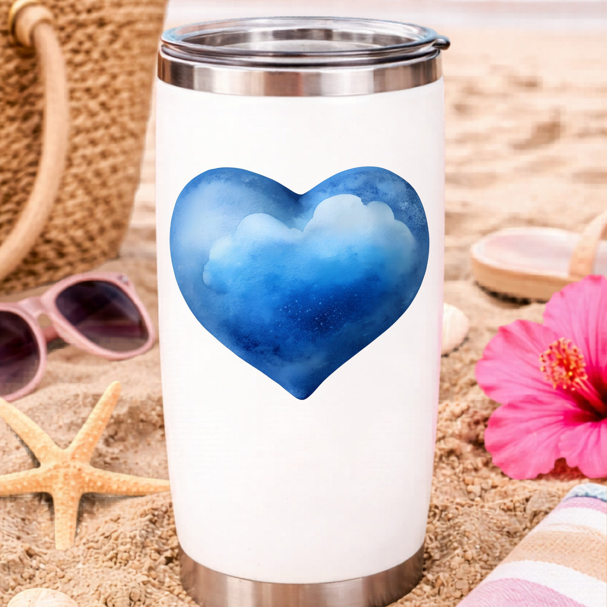 Blue Watercolor Heart With Clouds UV DTF sticker applied to a white travel tumbler on beach sand