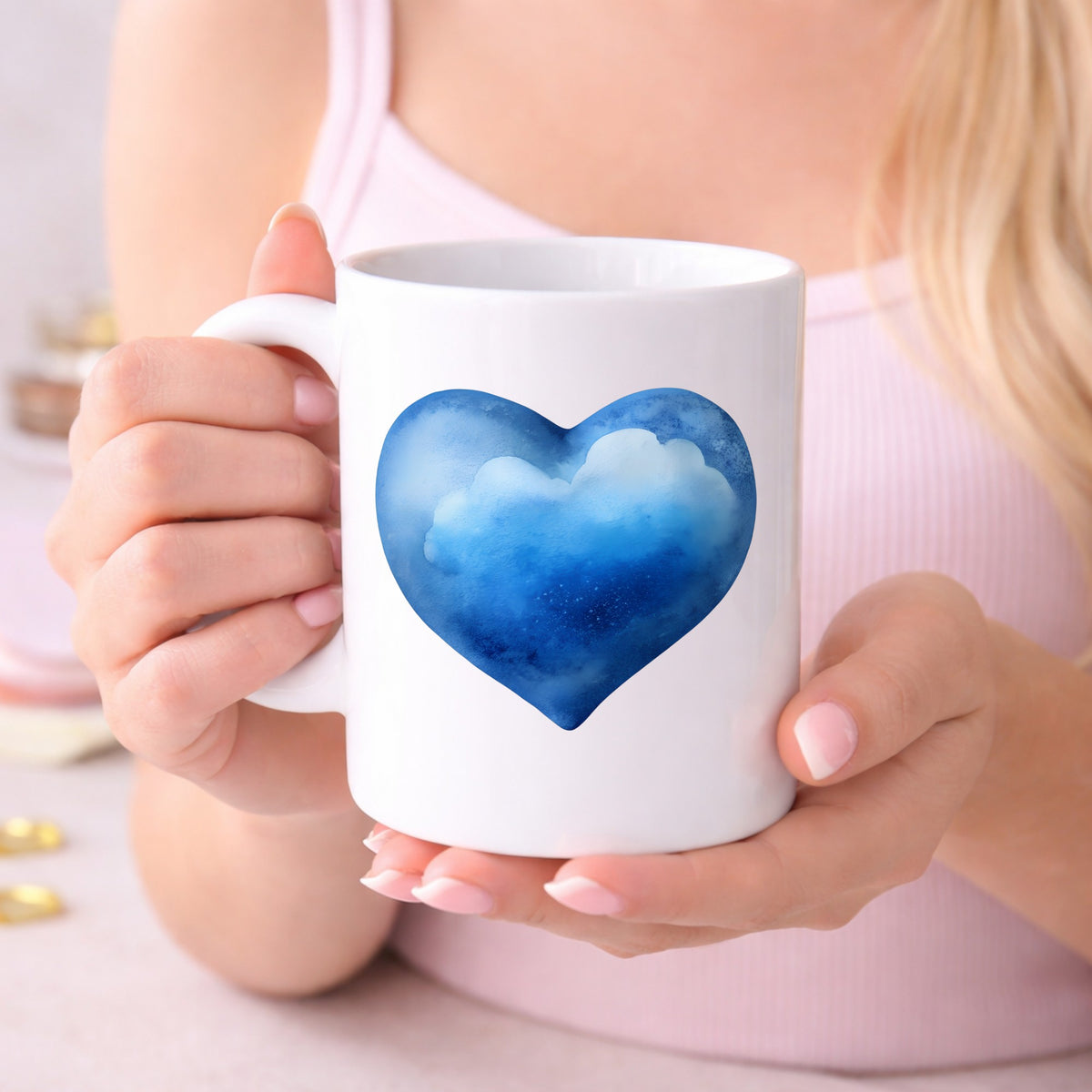 Blue Watercolor Heart With Clouds UV DTF sticker applied to a white coffee mug held in both hands