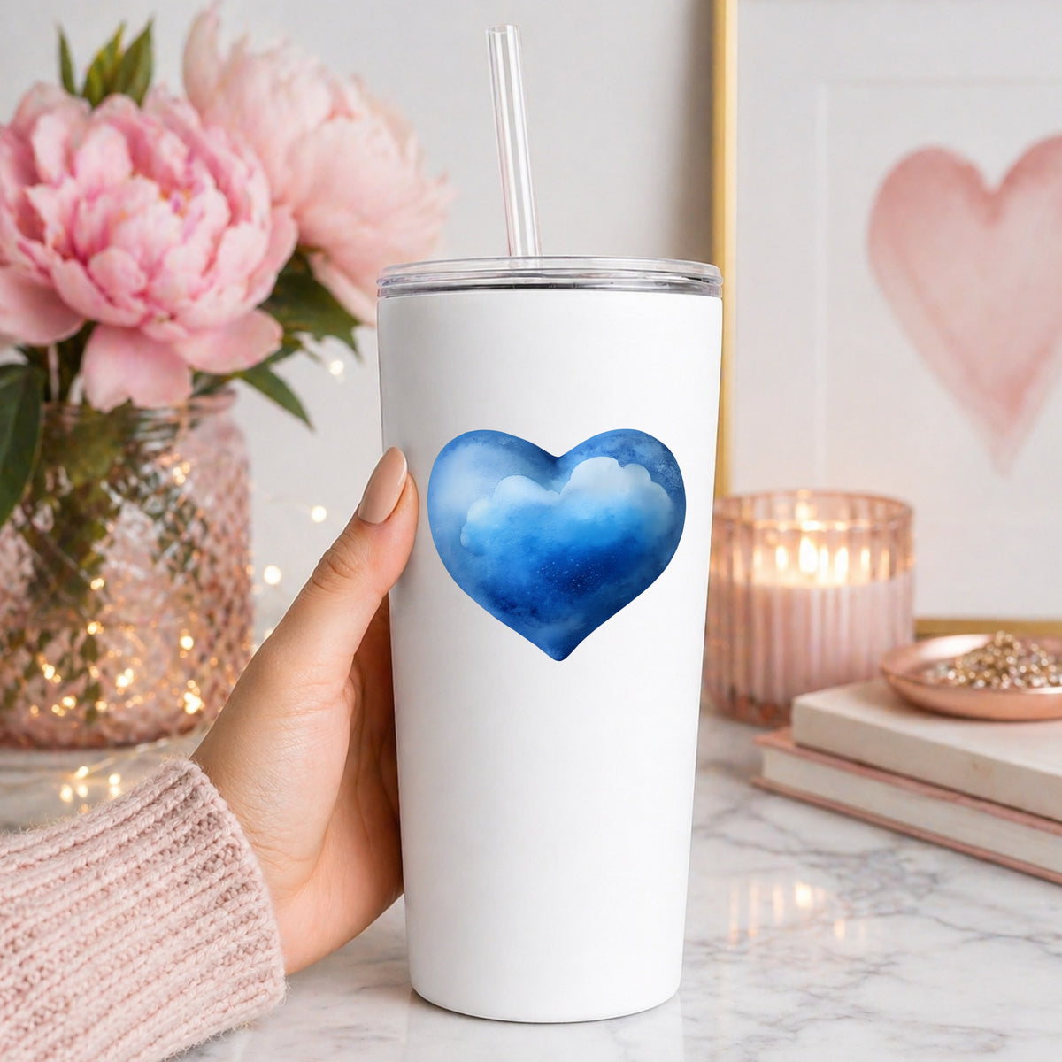 Blue Watercolor Heart With Clouds UV DTF sticker applied to a white straw tumbler beside pink peonies