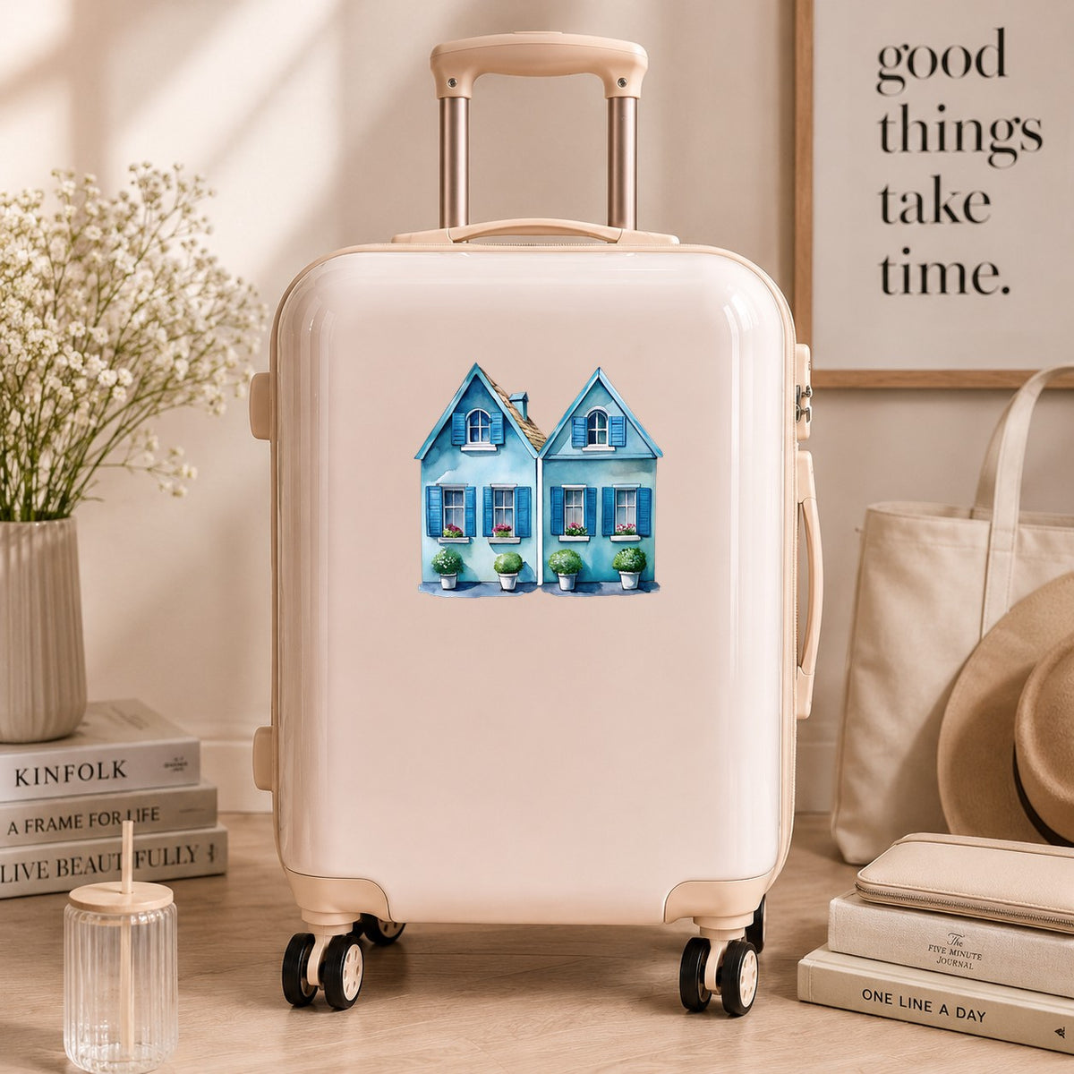 Two Blue Coastal Cottages UV DTF sticker applied to a cream carry-on suitcase