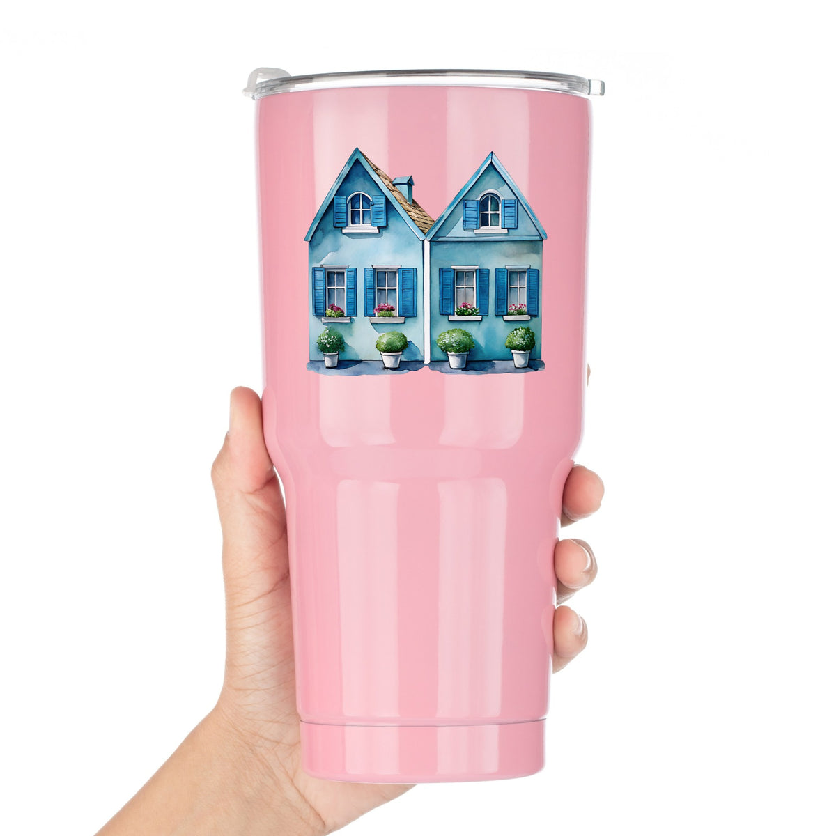 Two Blue Coastal Cottages UV DTF sticker applied to a pink tumbler held against a white background