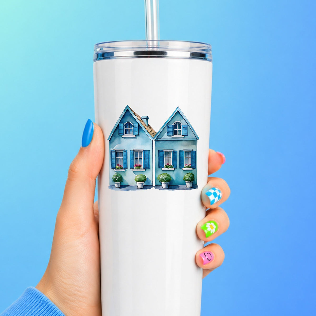 Two Blue Coastal Cottages UV DTF sticker applied to a white straw tumbler on a blue background